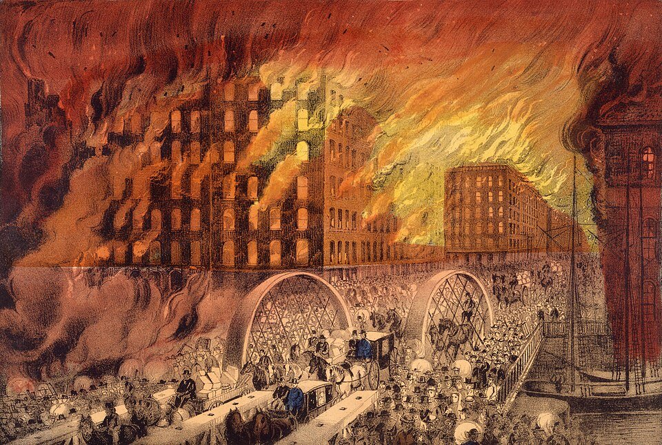 A colour lithograph of a city on fire, whole blocks of tall buildings wrapped in orange flame, with crowds and carriages streaming across an arched bridge in the foreground.