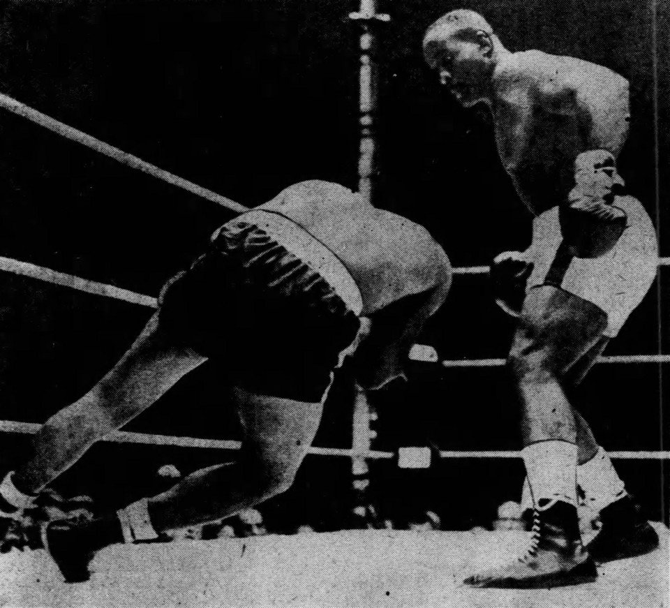 A boxer pitching forward onto the canvas while his opponent stands over him in a ring.