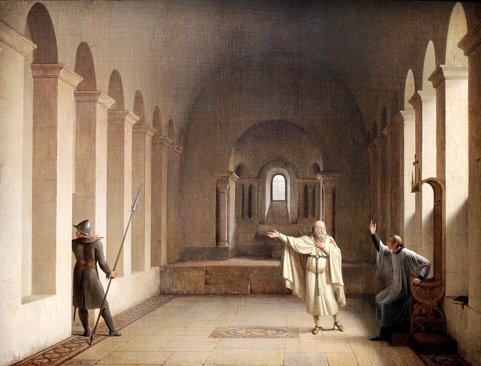 A painting of a bearded old man in a white mantle with a red cross, chained at the ankles, standing with arms outstretched in a vaulted stone chamber while a guard with a spear watches from a doorway.